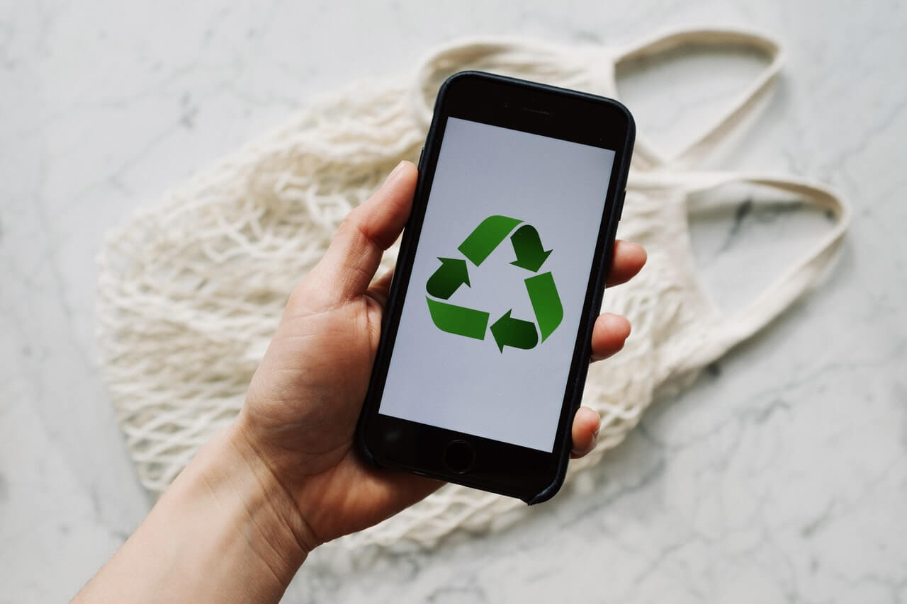Person holding a phone that is displaying recycle on the screen